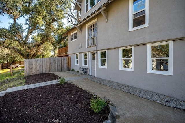 view of side of home featuring fence and stucco siding