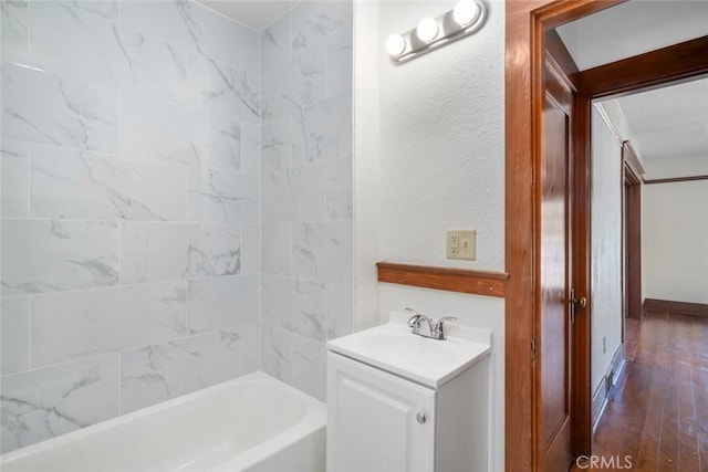 full bath with vanity, shower / bathing tub combination, wood finished floors, and a textured wall