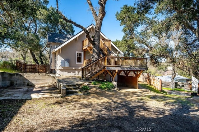 rear view of property with stairway, stucco siding, a deck, and fence