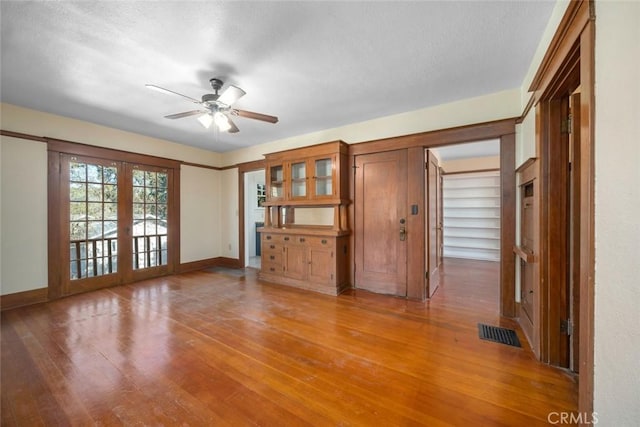 unfurnished living room featuring light wood-style flooring, french doors, visible vents, and baseboards