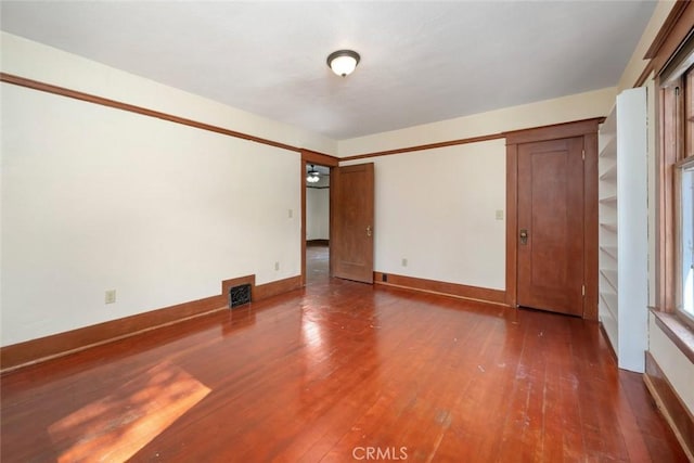 empty room featuring visible vents, baseboards, and hardwood / wood-style floors