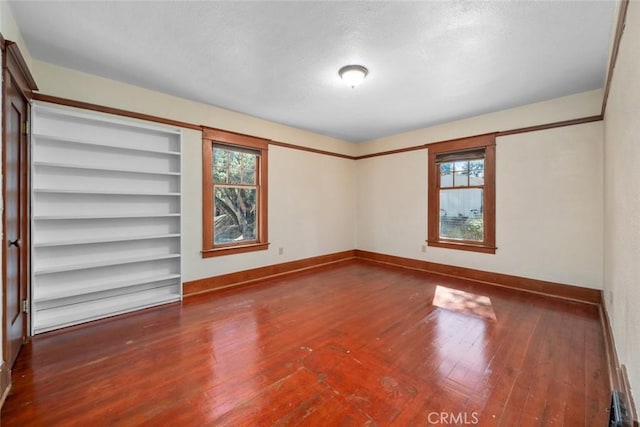 spare room with baseboards, plenty of natural light, a textured ceiling, and hardwood / wood-style flooring