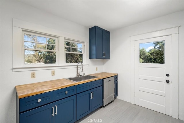 kitchen featuring a sink, wood counters, blue cabinetry, and stainless steel dishwasher