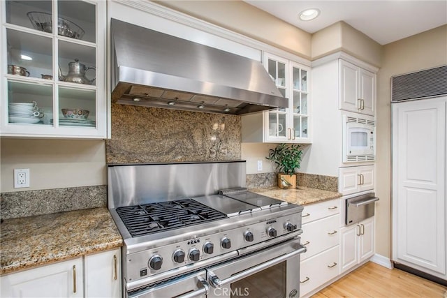 kitchen with tasteful backsplash, wall chimney exhaust hood, built in appliances, white cabinetry, and a warming drawer