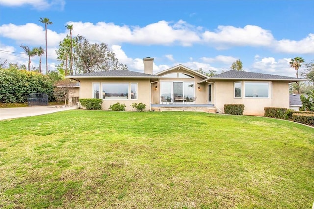 single story home with a chimney, a front lawn, and stucco siding