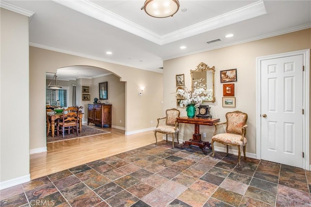 sitting room with baseboards, visible vents, arched walkways, stone finish floor, and a tray ceiling