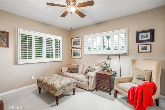 living area featuring carpet floors, baseboards, and a ceiling fan