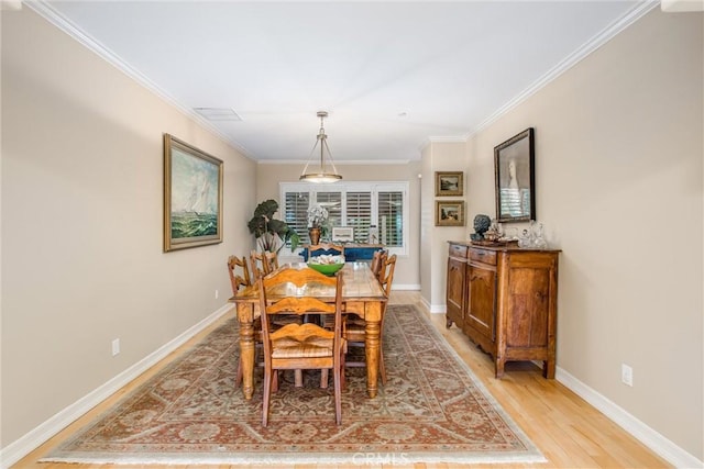 dining area featuring visible vents, crown molding, light wood-style flooring, and baseboards