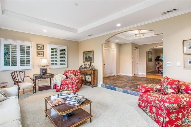 carpeted living area with visible vents, arched walkways, a tray ceiling, and recessed lighting