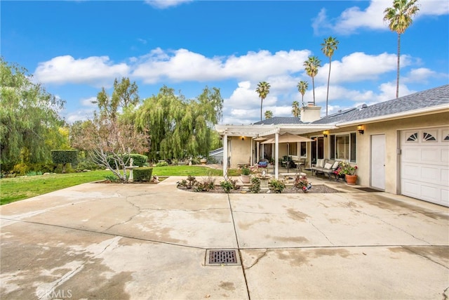 view of front of house with a garage, driveway, stucco siding, a chimney, and a patio area