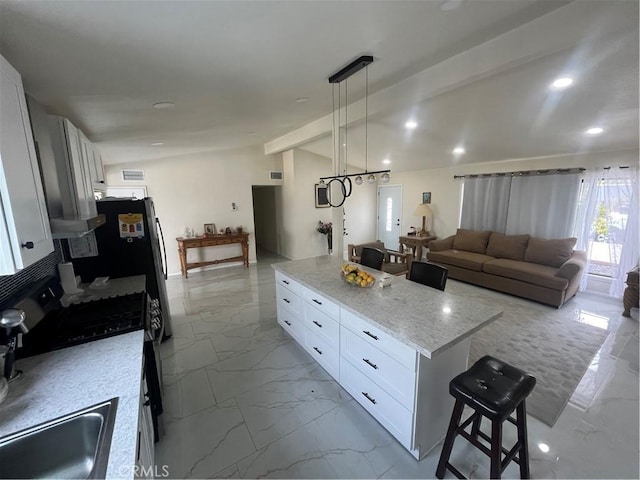 kitchen featuring marble finish floor, lofted ceiling with beams, white cabinetry, a kitchen island, and stainless steel gas range