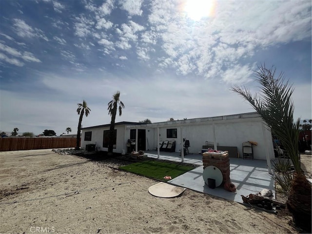 rear view of property with a patio area, fence, and stucco siding