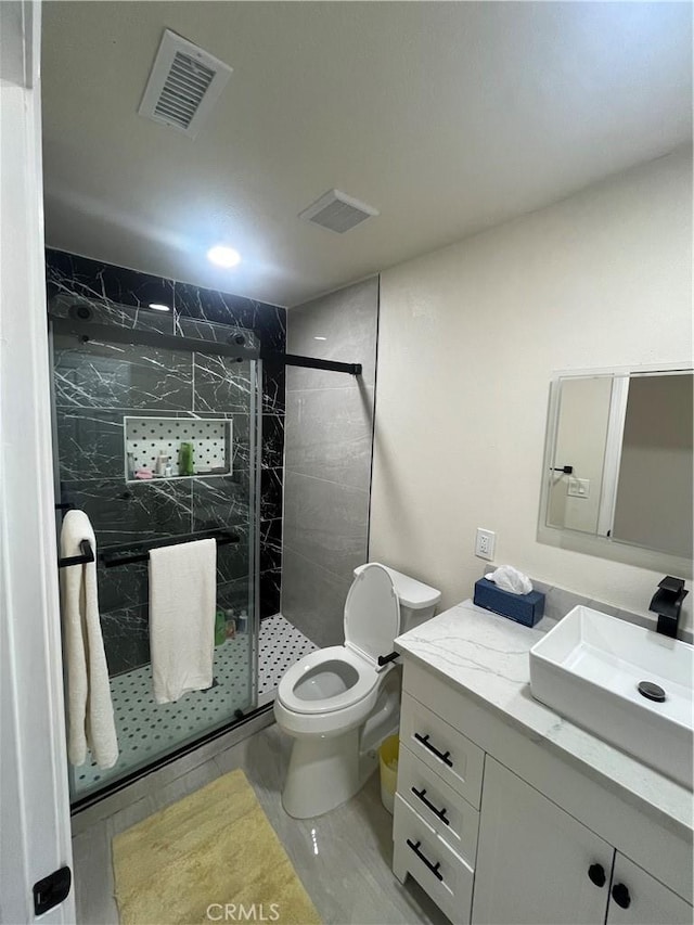 bathroom with a stall shower, visible vents, vanity, and toilet