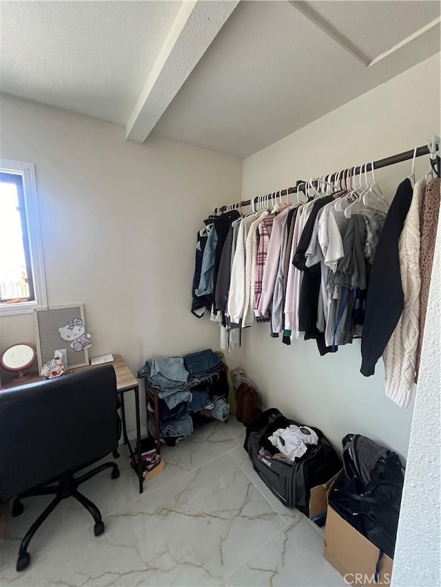 walk in closet with marble finish floor and beam ceiling