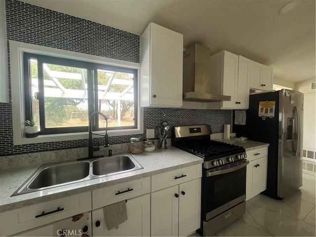 kitchen featuring marble finish floor, tasteful backsplash, appliances with stainless steel finishes, a sink, and wall chimney range hood