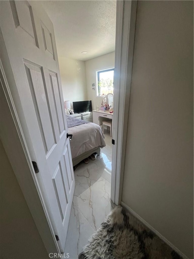 bedroom with marble finish floor, baseboards, and a textured ceiling