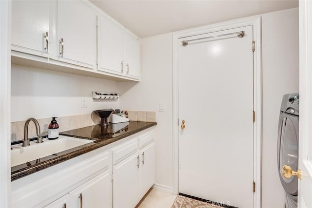 kitchen featuring dark stone counters, separate washer and dryer, a sink, and white cabinetry