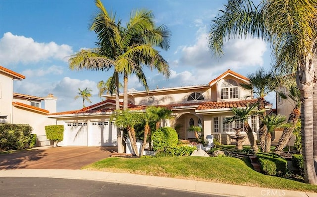 mediterranean / spanish-style house with driveway, stucco siding, an attached garage, and a tiled roof