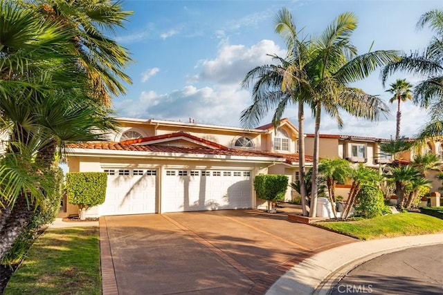 mediterranean / spanish-style house featuring concrete driveway, an attached garage, a tile roof, and stucco siding