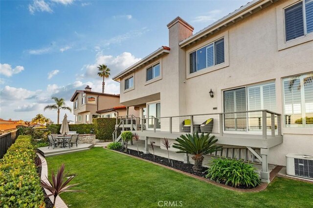rear view of property with a chimney, central AC, a yard, a patio, and stucco siding