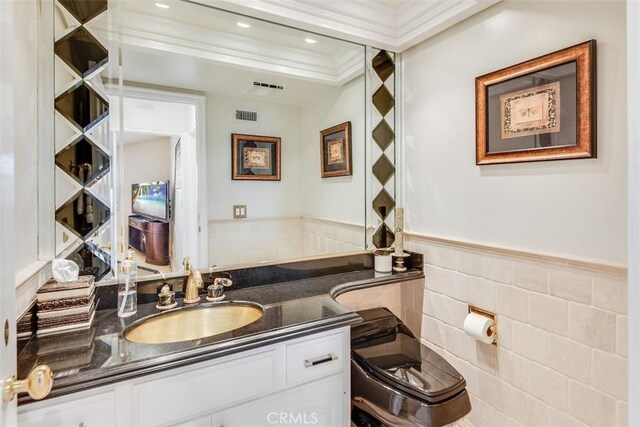 bathroom with visible vents, wainscoting, tile walls, and vanity