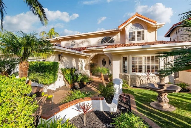 mediterranean / spanish home with a garage, a front yard, a tile roof, and stucco siding