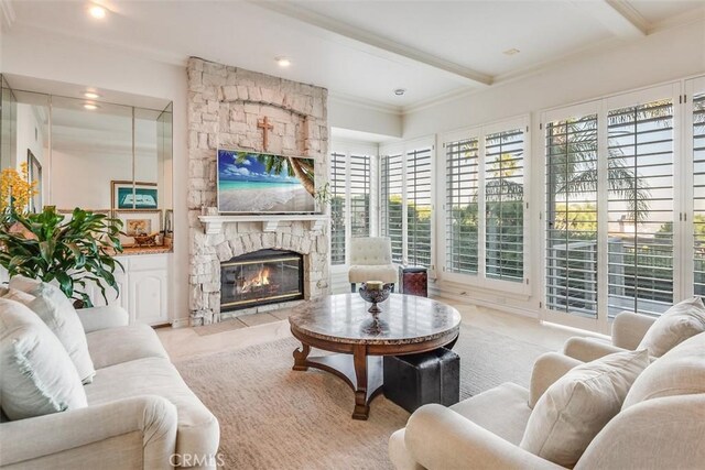 living room with crown molding, a fireplace, beam ceiling, and a wealth of natural light