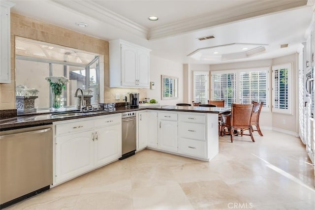 kitchen with a peninsula, a sink, ornamental molding, stainless steel dishwasher, and a tray ceiling