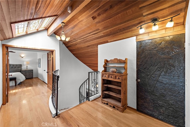 hall with an upstairs landing, wood ceiling, wood finished floors, and vaulted ceiling with skylight