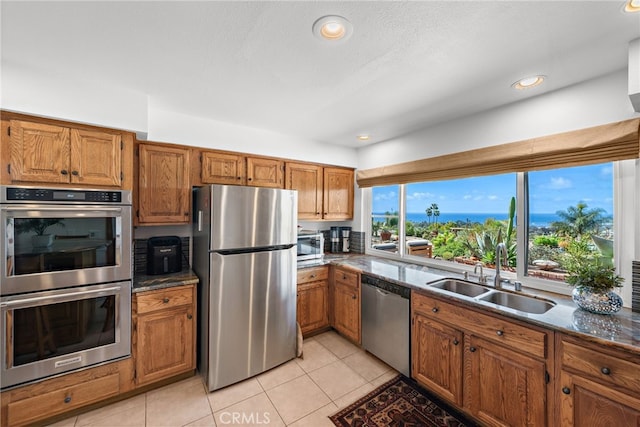 kitchen featuring brown cabinetry, light tile patterned floors, and stainless steel appliances