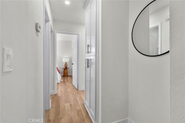 hall featuring light wood-style flooring and baseboards