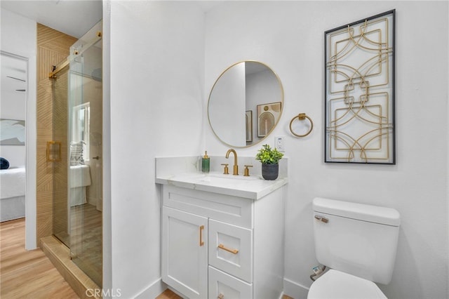 ensuite bathroom featuring toilet, a shower stall, ensuite bath, wood finished floors, and vanity