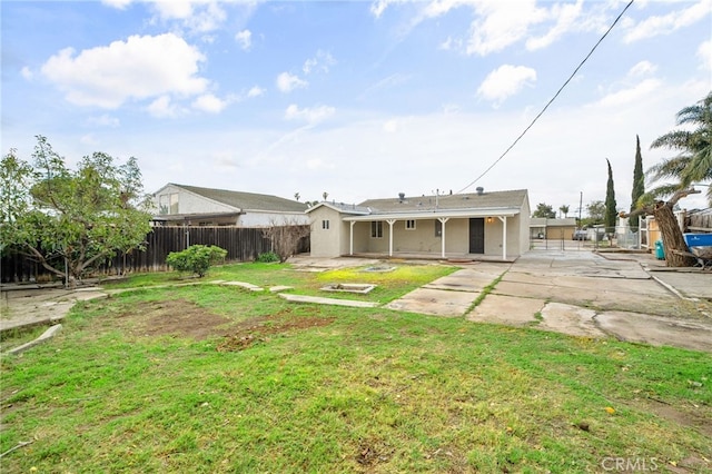 rear view of property featuring a patio area, a fenced backyard, a lawn, and stucco siding