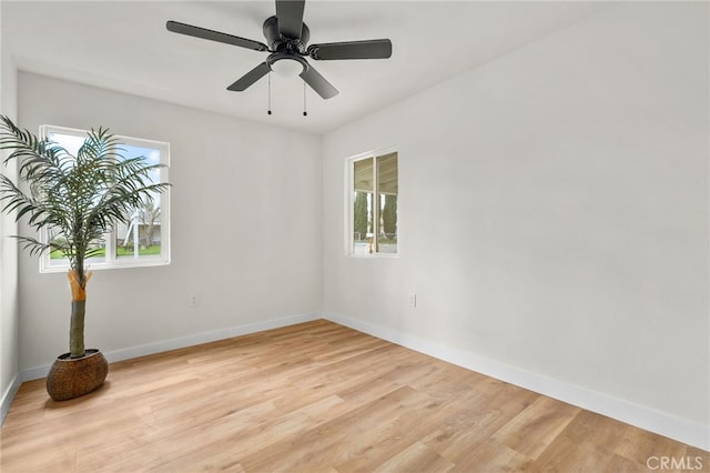 spare room with light wood-type flooring, a wealth of natural light, and baseboards