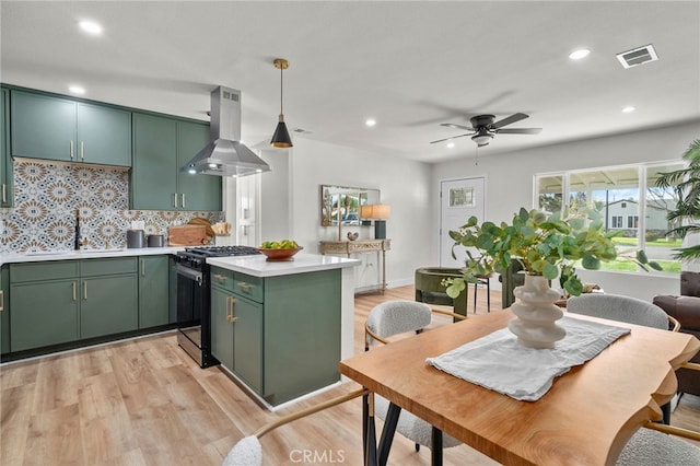 kitchen with stainless steel range with gas cooktop, light countertops, visible vents, island range hood, and green cabinetry