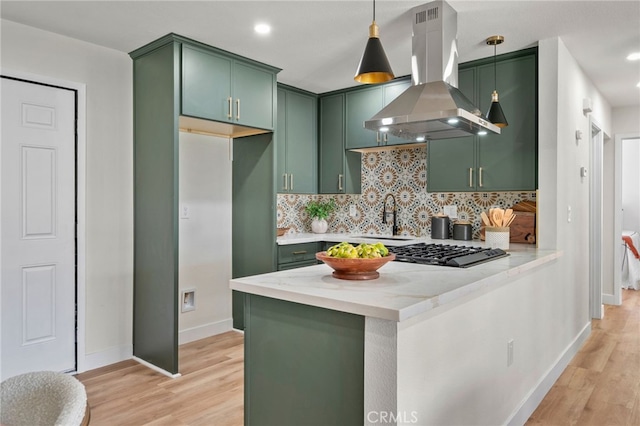 kitchen with decorative backsplash, island exhaust hood, light wood-style floors, and green cabinetry