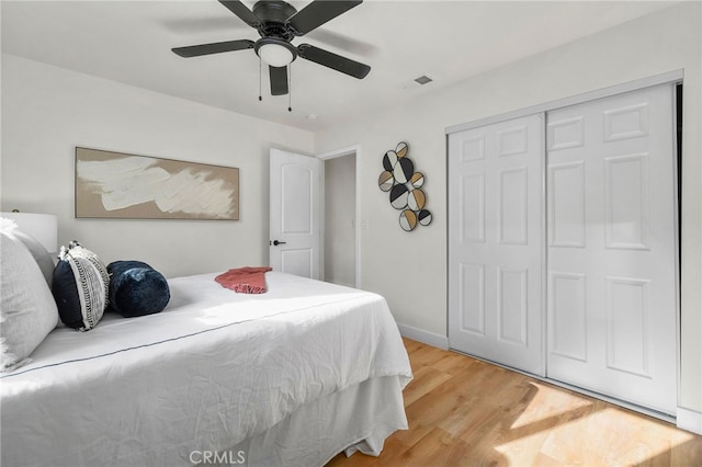 bedroom featuring a closet, visible vents, light wood-style floors, a ceiling fan, and baseboards