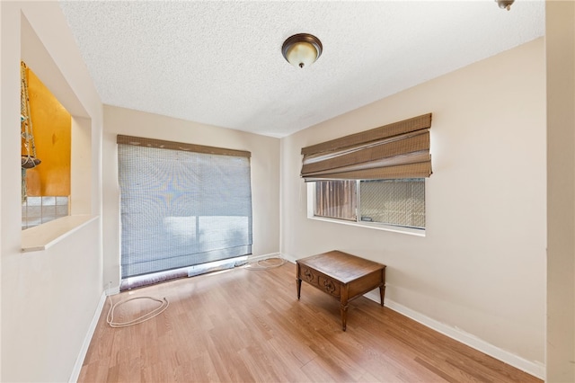 empty room with a textured ceiling, baseboards, and wood finished floors