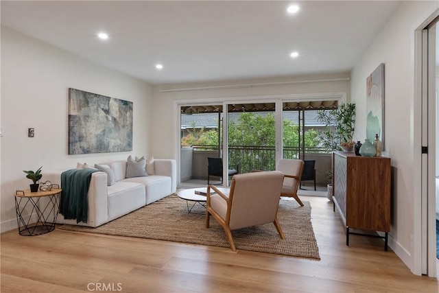 living area with baseboards, light wood-type flooring, and recessed lighting