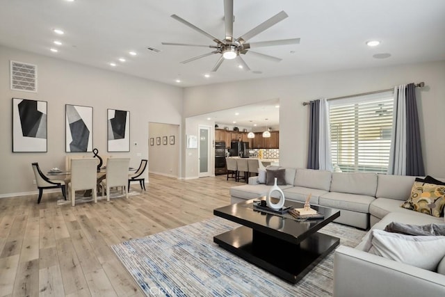 living room featuring a ceiling fan, baseboards, light wood-style flooring, recessed lighting, and vaulted ceiling