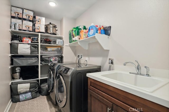 clothes washing area with cabinet space, washing machine and dryer, and a sink