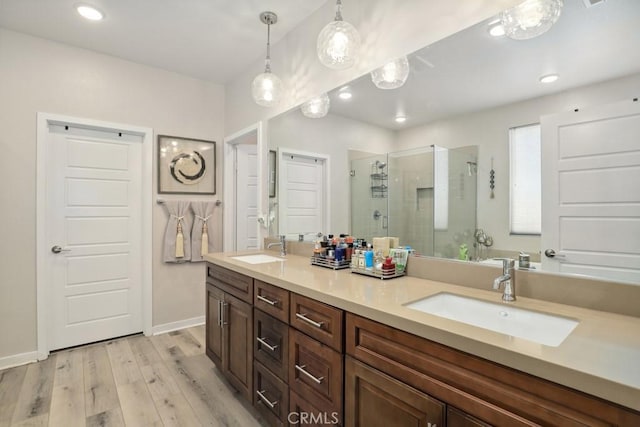 full bath featuring a shower stall, wood finished floors, double vanity, and a sink