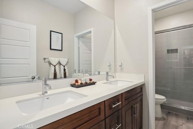 full bathroom with a shower stall, toilet, wood finished floors, and a sink