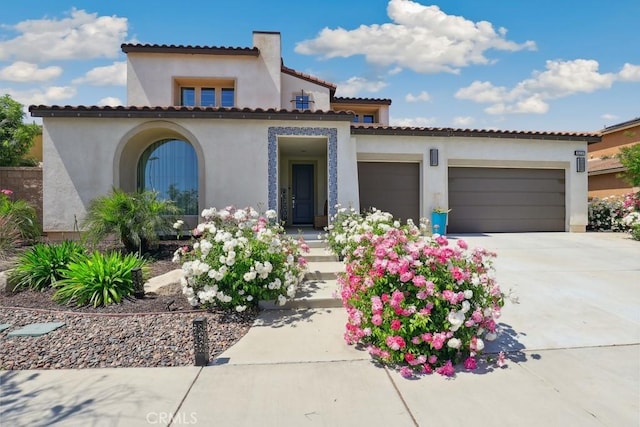 mediterranean / spanish-style house with stucco siding, an attached garage, and concrete driveway