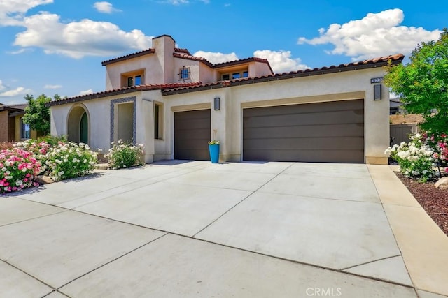 mediterranean / spanish house featuring a tile roof, concrete driveway, a garage, and stucco siding