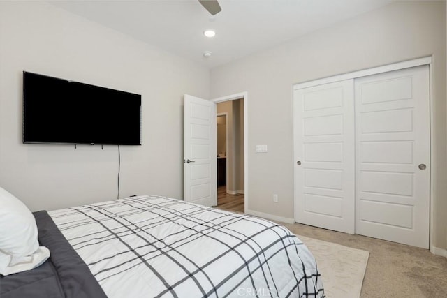 bedroom with light carpet, ceiling fan, a closet, and baseboards