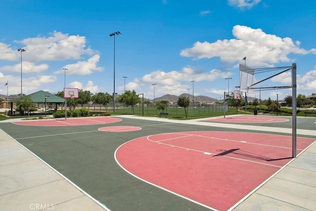 view of basketball court with a mountain view, community basketball court, and fence