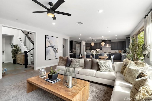 living room with recessed lighting, visible vents, baseboards, light wood-style floors, and stairway