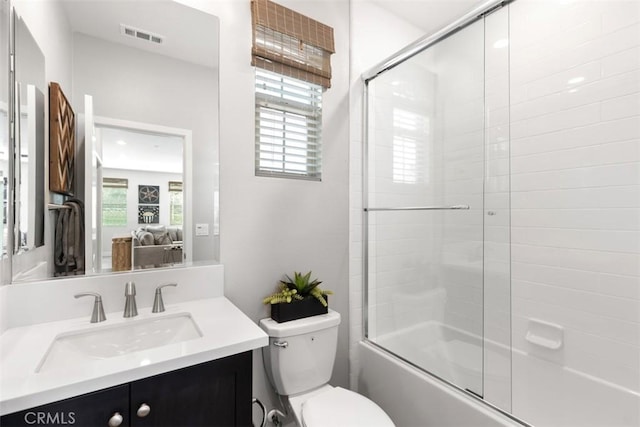 bathroom featuring toilet, vanity, visible vents, and a healthy amount of sunlight