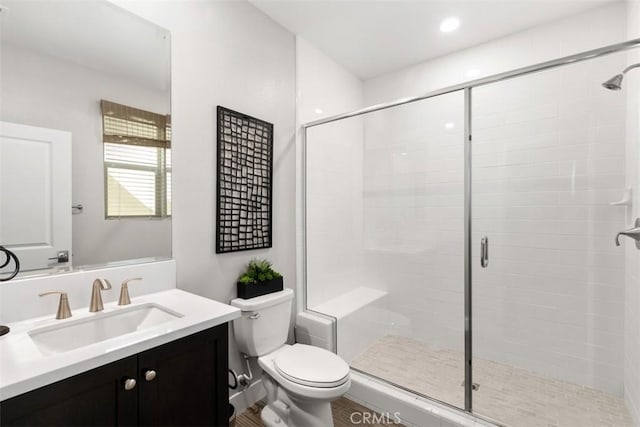 bathroom featuring toilet, a stall shower, recessed lighting, and vanity